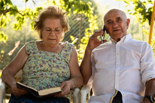 Para Seniorów Czytająca Książkę Rozmawiająca Przez Telefon Komórkowy — Zdjęcie stockowe