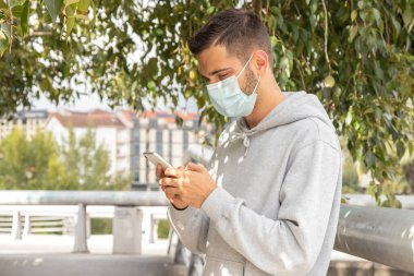 Maskeli ve telefonlu genç adam şehir dışında.