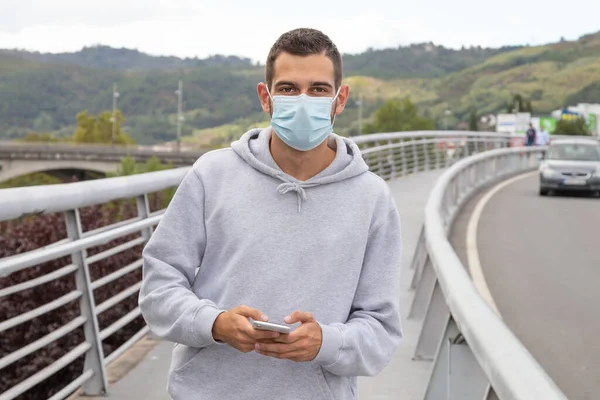 young man with mask and phone in the city outdoors