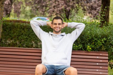 Genç adam sakin ve rahatlamış bir ifadeyle dışarıda.