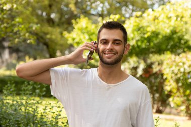 Dışarıda cep telefonuyla konuşan sakallı çekici bir genç adam.