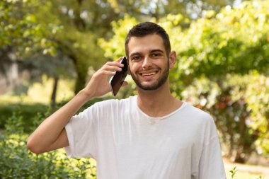 Dışarıda cep telefonuyla konuşan sakallı çekici bir genç adam.
