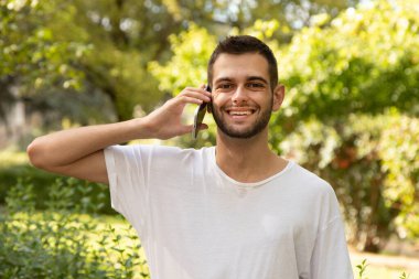 Dışarıda cep telefonuyla konuşan sakallı çekici bir genç adam.