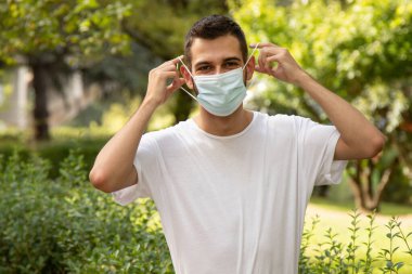 Genç adam dışarıda maske takıyor.