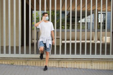 Maskeli ve cep telefonlu genç bir adam.