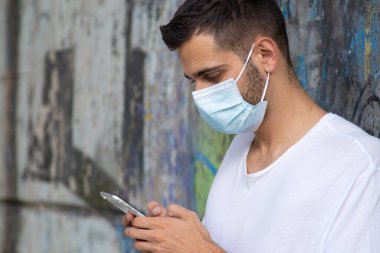 Maskeli ve cep telefonlu bir gencin portresi