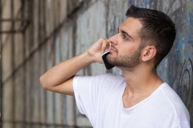 Sokakta cep telefonu olan genç bir adamın portresi.