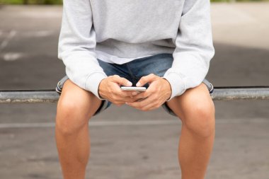 Genç adamın ellerini cep telefonuyla kapat.