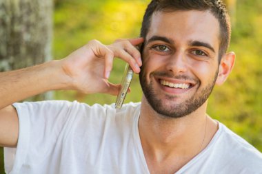 Dışarıda bilgisayarla çalışan çekici bir genç adam.