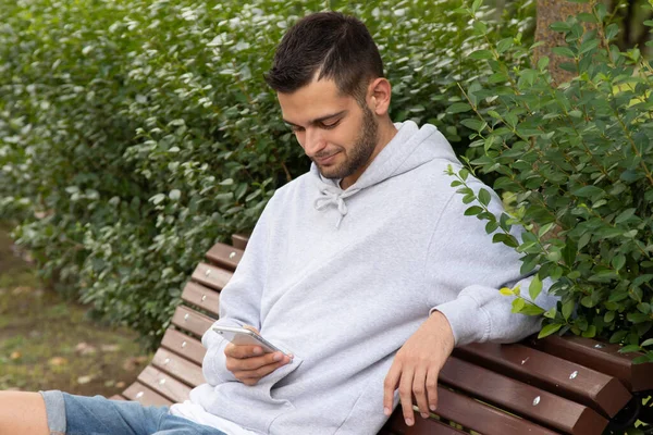 Jonge Man Met Mobiele Telefoon Het Park Zit — Stockfoto