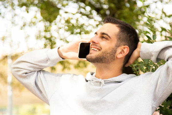 有魅力的年轻人 留着胡子 拿着手机坐在公园里 — 图库照片