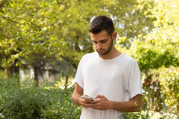 屋外で携帯電話を持つ魅力的な若い男 — ストック写真