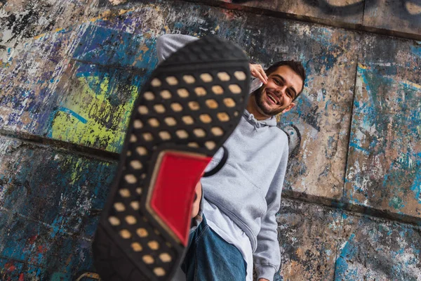 Jongeman Met Mobiele Telefoon Staand Voor Camera Vlekken Verfspaanders Muur — Stockfoto