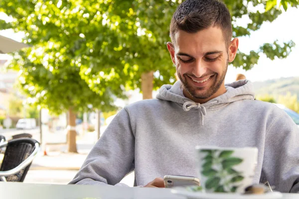 young man in cafe terrace with mobile phone