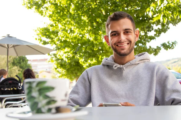 young man in cafe terrace with mobile phone