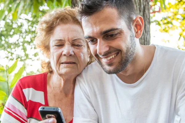 young man with mobile phone and old woman outdoors