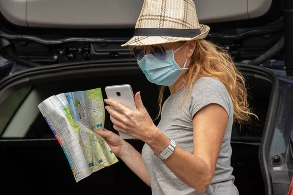 adult woman traveling by car with mask and map