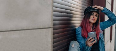 Sokakta cep telefonu ya da akıllı telefonu olan genç bir kadın.