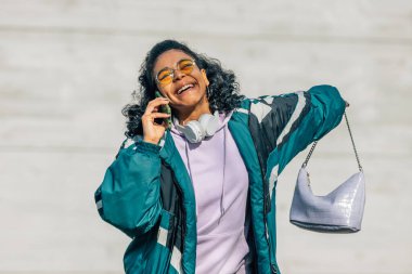 Klasik tarzı olan genç bir kadın sokakta cep telefonuyla konuşuyor.