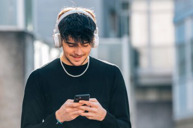 Kulaklık ve cep telefonu olan genç bir adam ya da öğrenci.