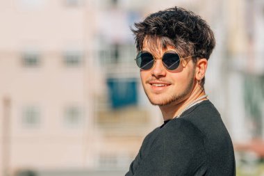 Sokakta güneş gözlüklü genç bir adamın portresi.