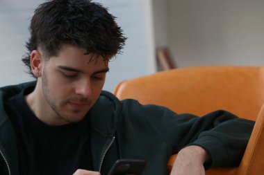 Cep telefonuyla rahatlamış genç bir adam ya da öğrenci