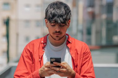 Sokakta cep telefonlu bir gencin yakın çekimi.