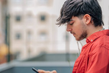 Sokakta cep telefonlu bir gencin yakın çekimi.