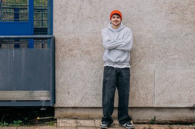 Sokak duvarında şapkası olan genç adam.