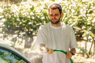 young man washing the car with the hose