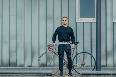 Sokak duvarı arka planı ve kopyalama alanı olan bisikletli genç bir adam.