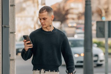 Sokakta bisikletli, cep telefonu olan şehirli genç bir adam.