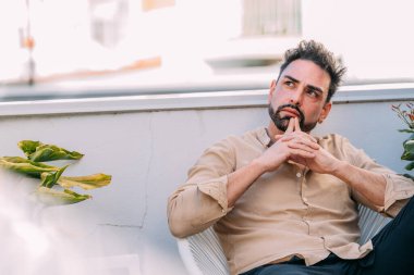 Evin terasındaki düşünceli genç adam.