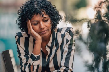 Stresli bir ifadeyle sokakta oturan bir kadın.