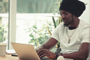 Masasında dizüstü bilgisayarlı genç Afrikalı bir adamın portresi.