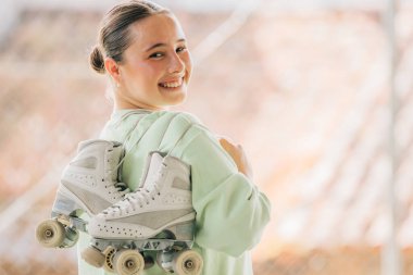 Patenleriyle dışarıda gülümseyen artistik patinaj sporcusu