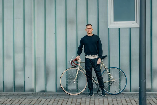 Sokak duvarı arka planı ve kopyalama alanı olan bisikletli genç bir adam.