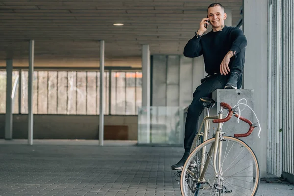 Bisikletli genç adam cep telefonuyla konuşuyor.
