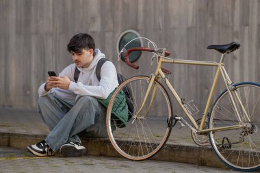 Cep telefonu ve klasik bisikleti olan genç bir adamın şehir manzarası