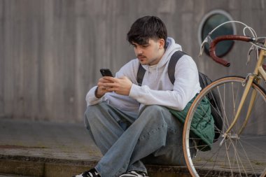 Cep telefonu ve klasik bisikleti olan genç bir adamın şehir manzarası