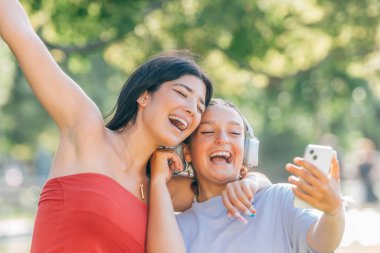 Sokakta eğlenen iki arkadaş cep telefonuna bakarak kahkaha atıyor.