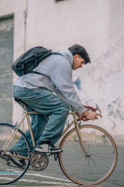 Sırt çantalı genç adam ya da öğrenci klasik bisiklete biniyor.