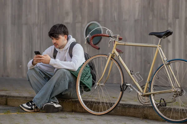 Cep telefonu ve klasik bisikleti olan genç bir adamın şehir manzarası
