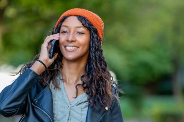 young latina woman talking on mobile phone on the street with hat and urban style
