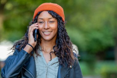 young latina woman talking on mobile phone on the street with hat and urban style