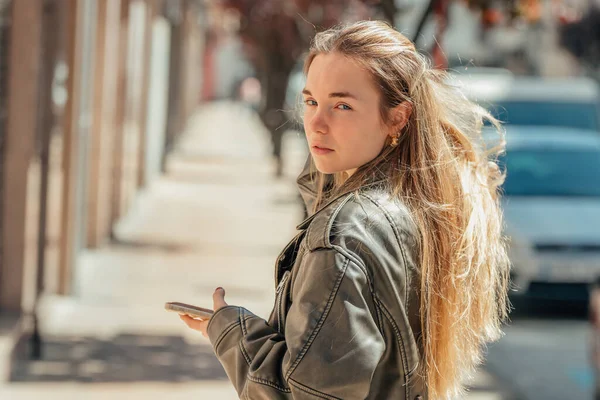 Sokakta cep telefonuyla dolaşan sarışın kız.