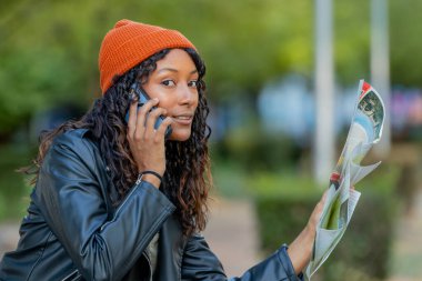 Haritalı kadın gezgin cep telefonuyla konuşuyor