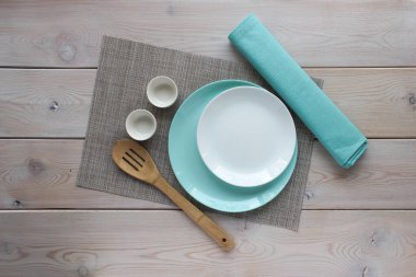Beyaz ve turkuaz tabak, ahşap mutfak kaşığı, turkuaz peçete. Model için..