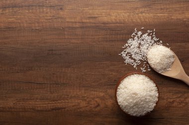 Bir kase ve tahta kaşık çiğ pirinç Yasemin üstten görünüm koyu ahşap masa, Tayland Yasemin pirinç üzerinde.