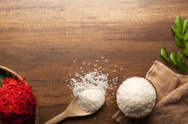 Yasemin pirinç bir kase ve tahta kaşıkla üstten görünüm üzerinde kırmızı çiçekli koyu ahşap masa.